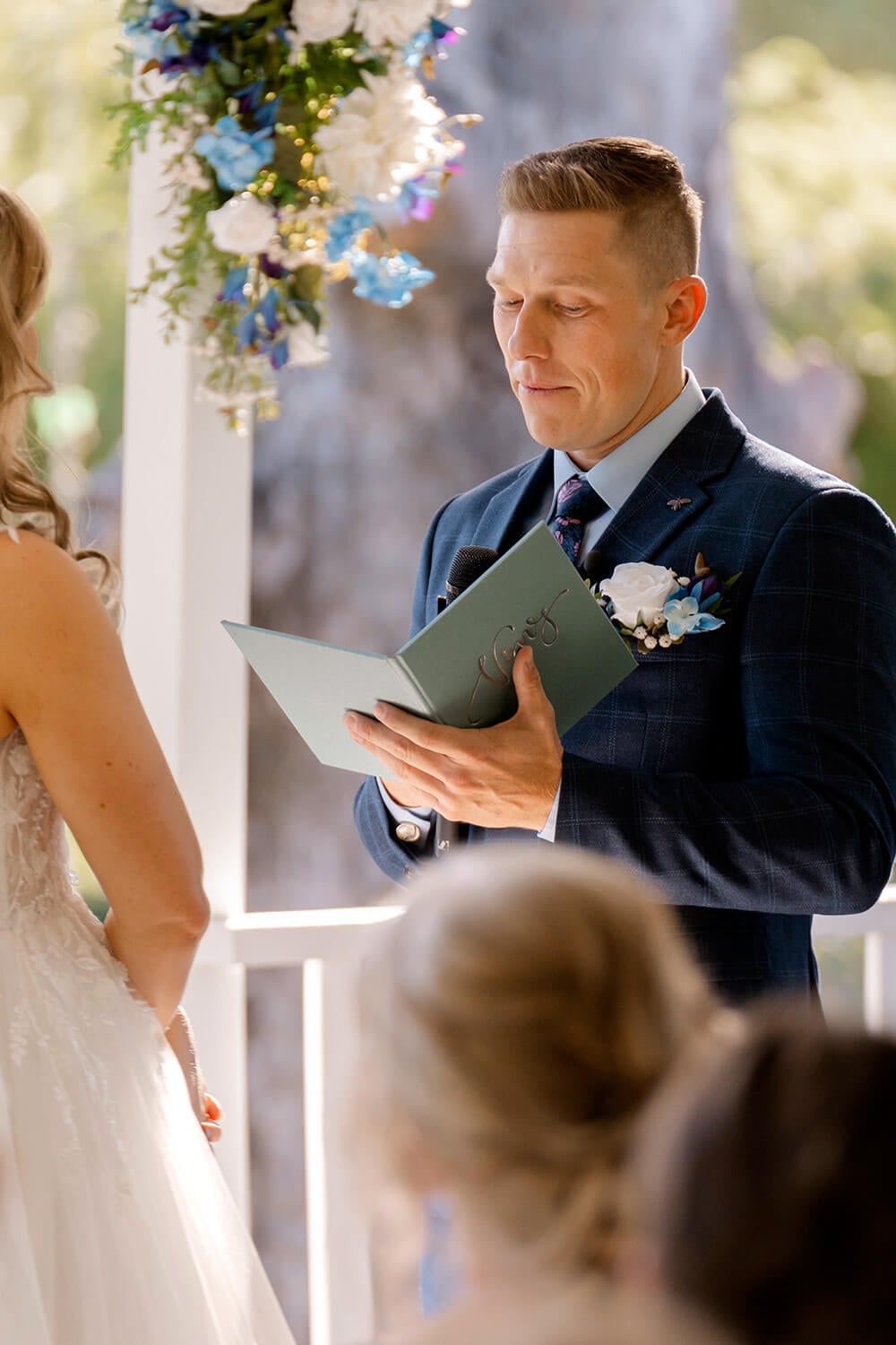 a groom reads his vows to his wife from a custom linen vow book during a wedding ceremony