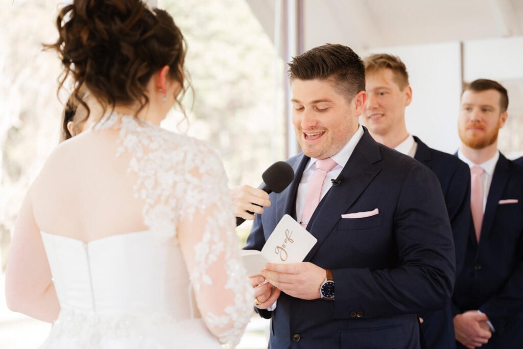 groom reading his vows to his wife using a love letter vow book during a ceremony.