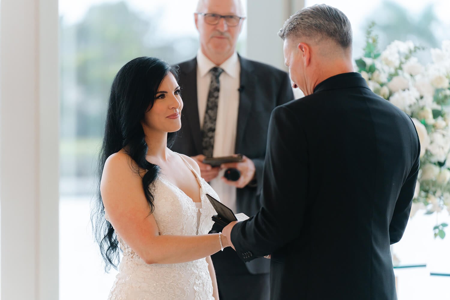 a groom reads his vows from a wooden wedding vow book during a wedding ceremony.