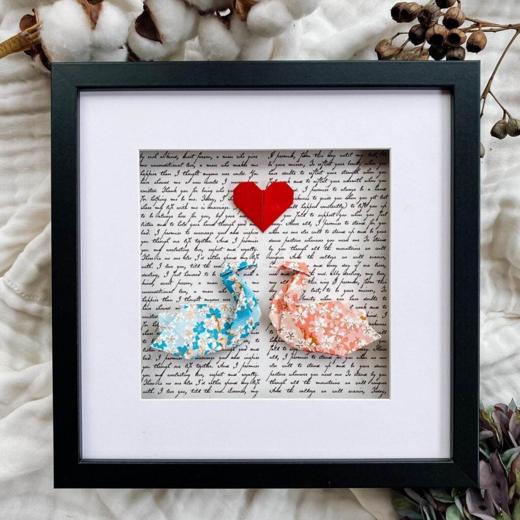 Origami swans made from personalised wedding vows displayed in a white 3D shadow box frame