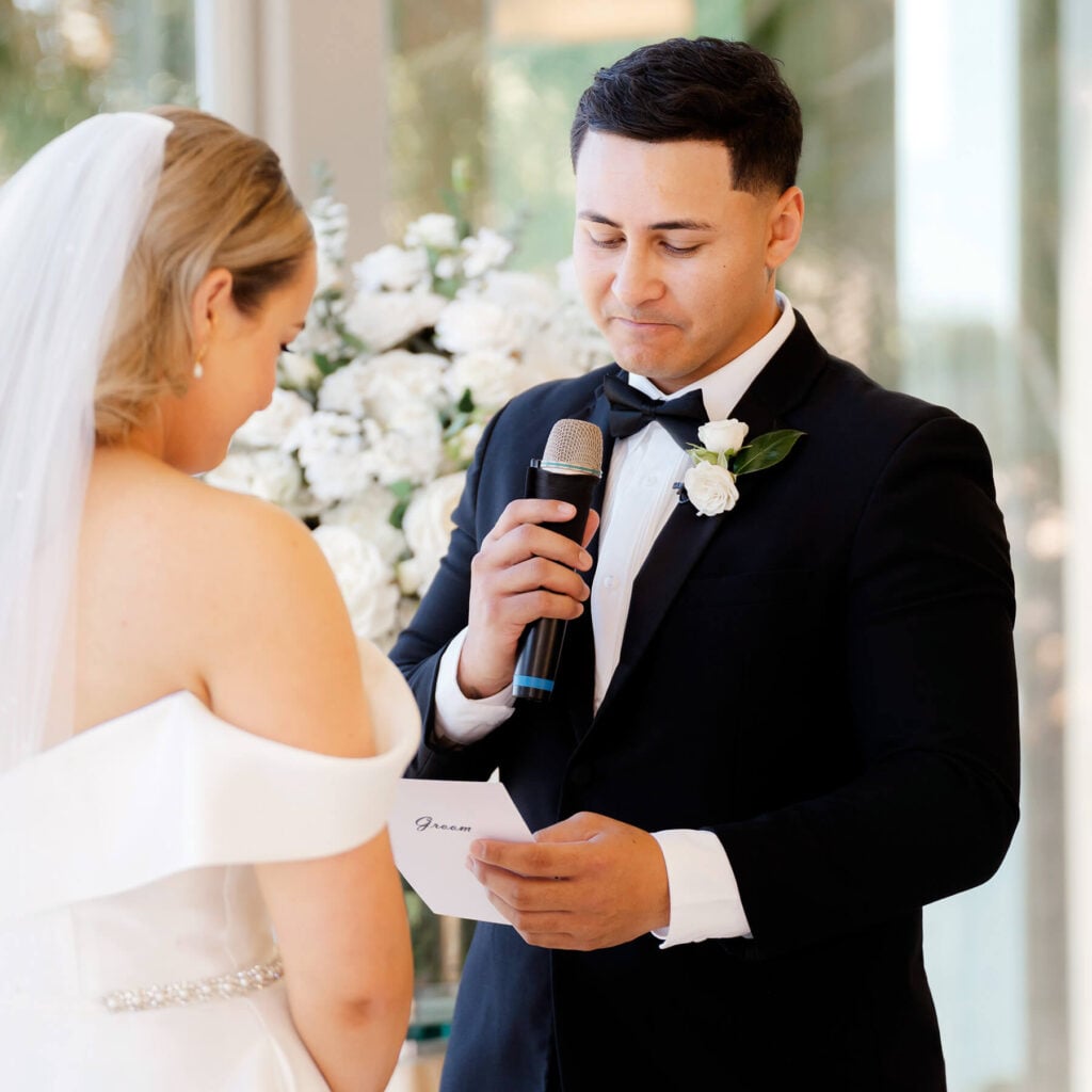 A groom tries to hold back tears while reading his wedding vows to his wife.